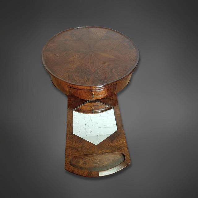 A round Biedermeier side table with an unusual construction. The body is veneered in walnut. The tabletop features a...