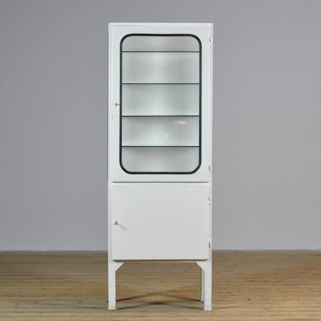 Vintage medicine cabinet from the 1970s, produced in Hungary. This cabinet is made of iron and glass, with the glass held...