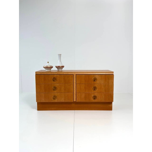 A compact chest of drawers in a mid-century-inspired retro style with six drawers and a warm wood finish. The clean,...