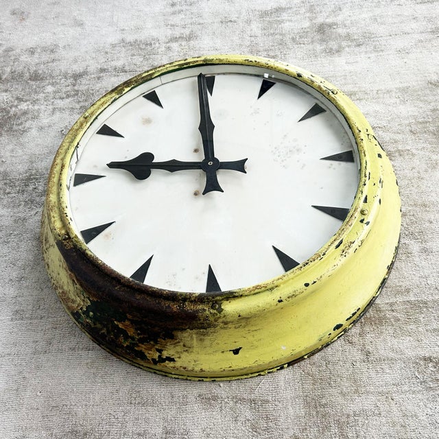 Large factory clock with domed metal case in cream-yellow painted finish. The 60cm diameter frame houses a white dial...