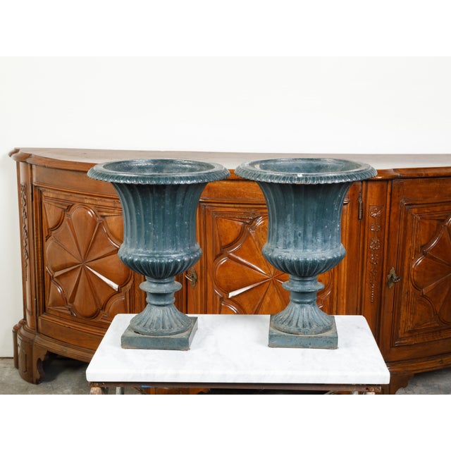 A pair of English iron Medici urn planters from the 19th century, with flaring lips and gadroon motifs. Created in England...