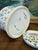 The ceramic pottery features a round body with a decorative design of colorful flowers and leaves, showcasing a vibrant...