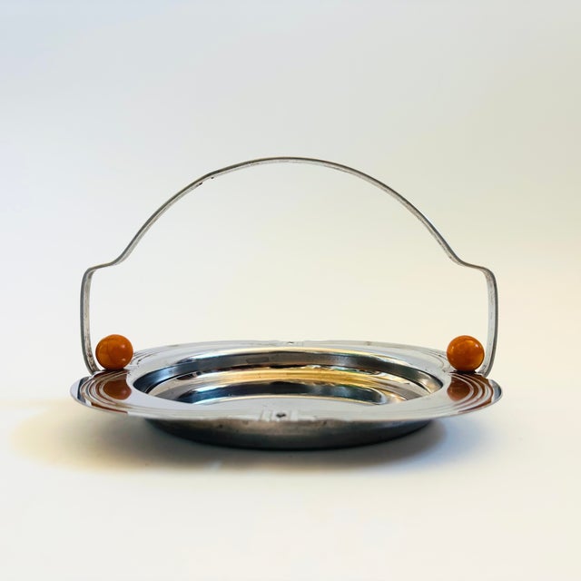 A vintage art decor chrome serving tray with a handle. Features spherical bakelite accents at the base of the handle and...