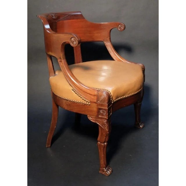 The desk chair with carved diamond motif on crest and richly carved griffin wings above articulated paw feet with tan...