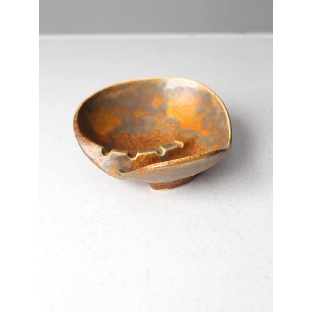 A mid-century Haeger pottery ashtray featuring sleek, dynamic lines and a bold, sculptural form. Finished in a striking...