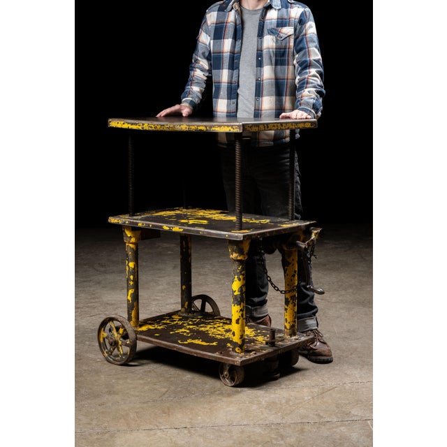 Vintage cast iron rolling industrial cart. This piece features three tiers of storage, with an adjustable-height top...