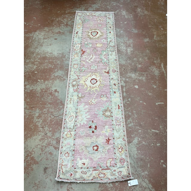 Turkish Oushak pink runner, hand-knotted in Afghanistan from 100% wool. Measuring 2’9” x 11’8”, the rug features a soft...