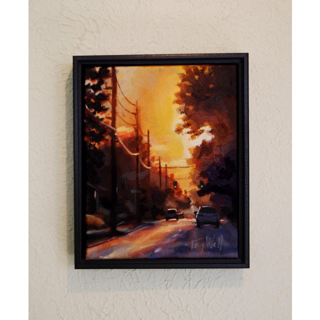 The artwork depicts a serene evening scene, where a warm golden light bathes the street and surrounding trees, creating a...