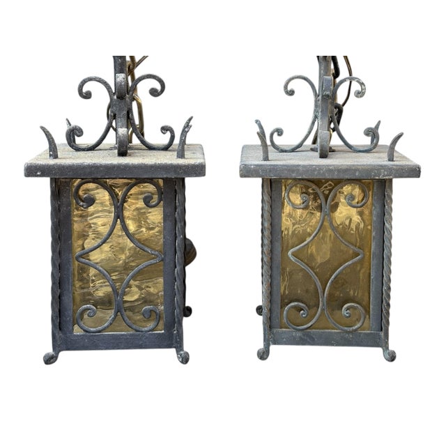 Pair of Italian pendant wall lanterns circa 1950. Amber glass panels are secured with scrolled and twisted wrought iron...