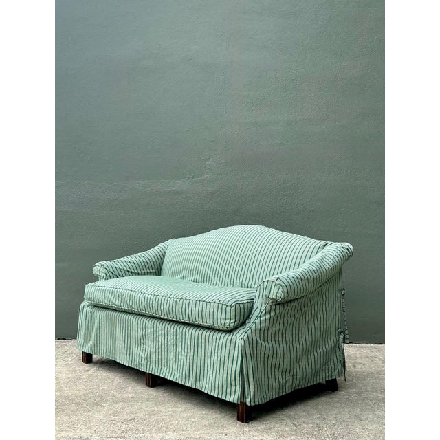 This vintage camelback settee is a charming embodiment of mid-century traditionalism, featuring a gracefully arched...