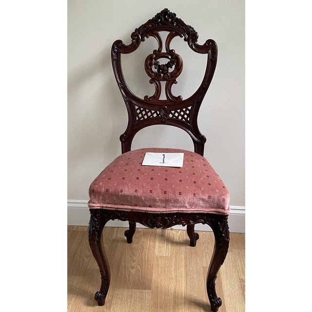 Timeless and stately, this pair of Victorian parlor chairs showcases hand-carved mahogany frames with rich floral tapestry...