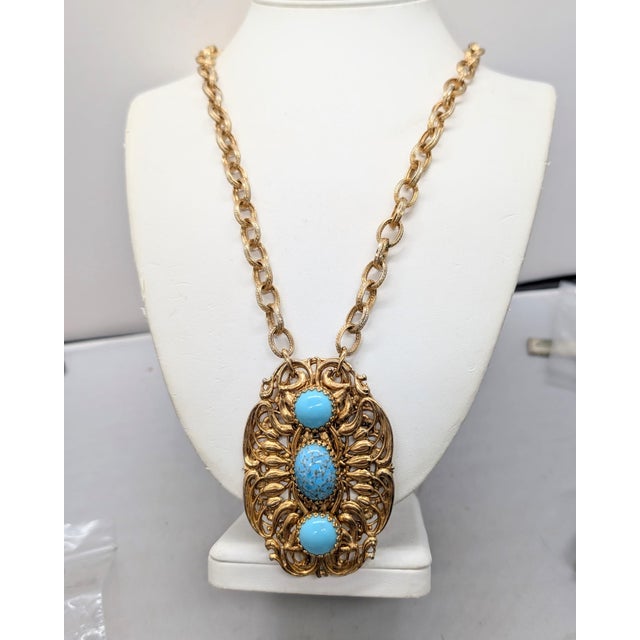 Rare 1960s goldtone ornate openwork pendant with a line of cabochon faux-turquoise down the center with a round top and...