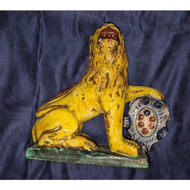 This is a vintage Italian majolica or faience ceramic figurine of a Medici-style lion resting its paw on an armorial...