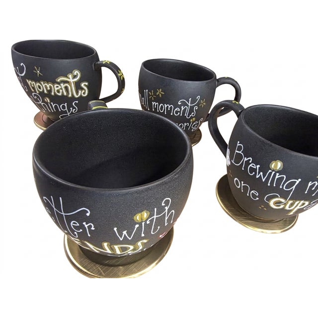 Handcrafted ceramic mugs feature a charming, artisan aesthetic with a matte black finish that serves as a canvas for...