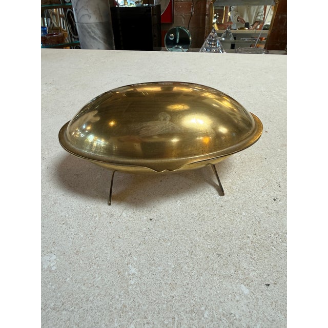 Unique vintage brass covered dish designed in an elegant clamshell form, raised on three delicate legs. The hinged lid...