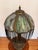 A stunning early 20th century slag glass table lamp, featuring a richly patinated cast metal Art Nouveau base with ornate...