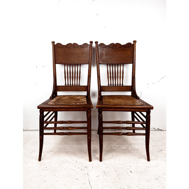 A pair of beautifully crafted spindle back pressed dining chairs with leather seats. These antique beauties are of solid...