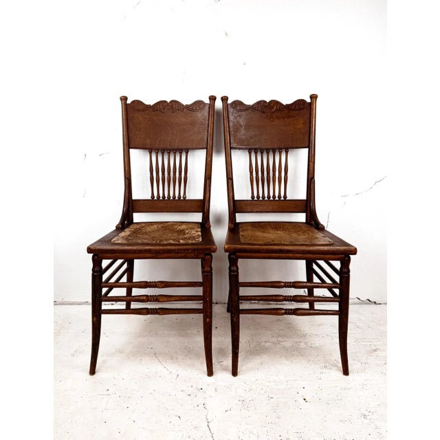 A pair of beautifully crafted spindle back pressed dining chairs with leather seats. These antique beauties are of solid...