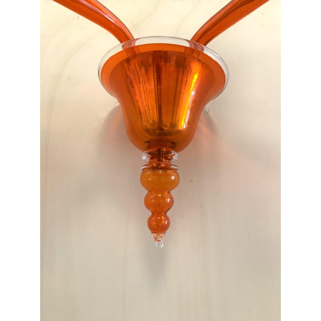 Contemporary Translucent Orange Glass wall sconce in Murano glass. Decorated in translucent orange colour which makes it...