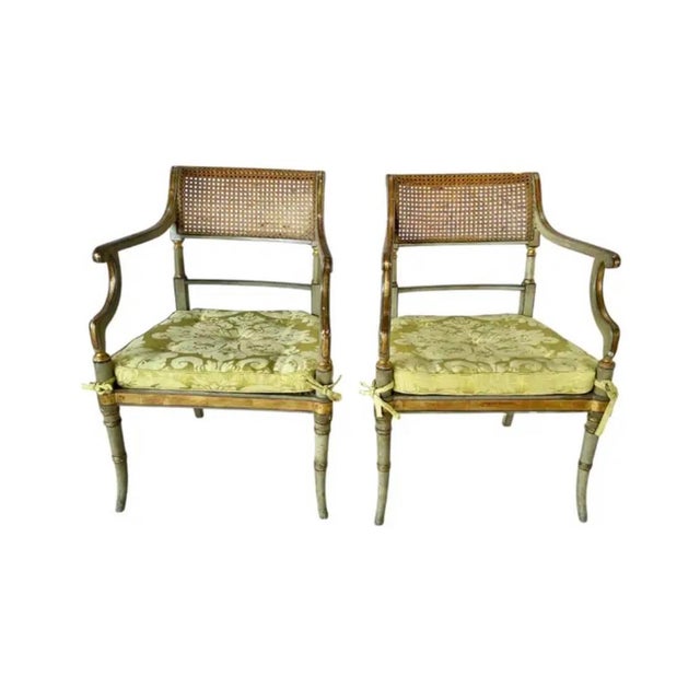 Refined Pair of Regency Painted Armchairs. Chairs feature painted wood with hand-caned backs and seats, gently curving...