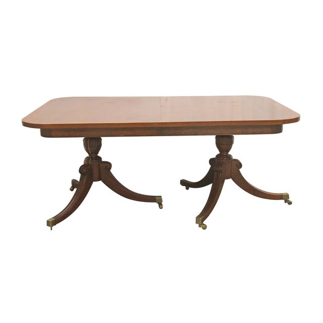 Duncan Phyfe style drop leaf table in dark wood tones. The tripartite (three-legged) bases that feature urn-shaped pillars...