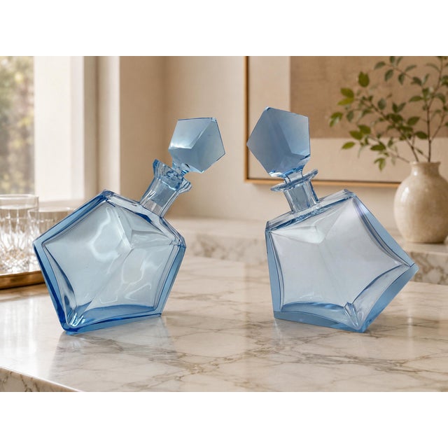 A striking pair of Mid-Century Modern sculptural art glass decanters crafted in a delicate light blue transparent glass....