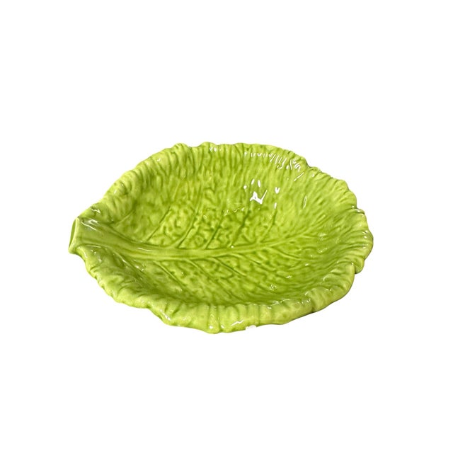 The bowl features a vibrant green majolica-style glaze, a textured surface mimicking vegetable leaves and a ruffled rim.