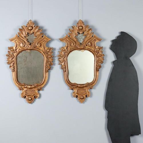 Pair of small Rococo-style mirrors in burnished gold-painted wood, with leaf carvings and scrolls, and mercury mirrors....