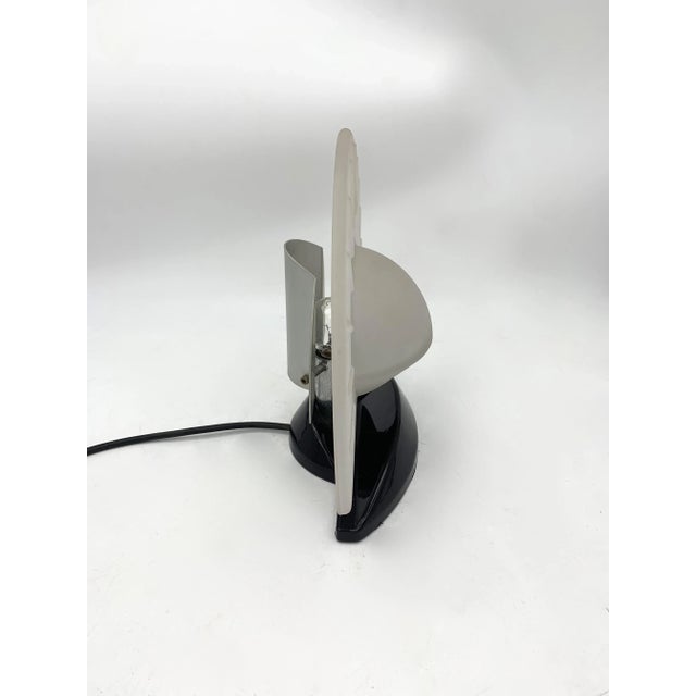 Art Deco style table lamp with a compact and geometric structure. The diffuser is made of semi-transparent satin glass,...