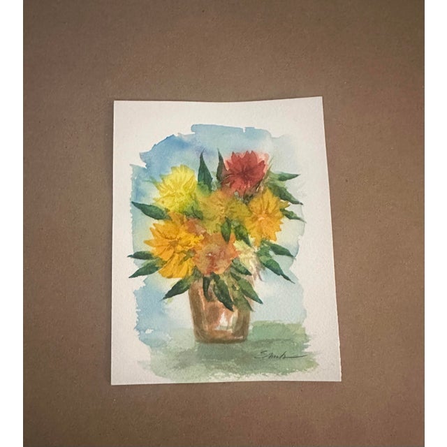 Original watercolor floral painting featuring a cheerful bouquet of golden yellow, coral, peach, and red blossoms arranged...
