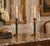A matching pair of hurricane lamps featuring tall, hand-blown clear glass shades enclosing classical-style candlesticks....
