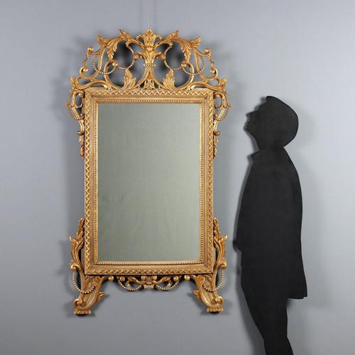 Carved, lacquered, and gilded wood mirror. The mirror is enclosed in a ribbed frame with geometric carvings on the top and...