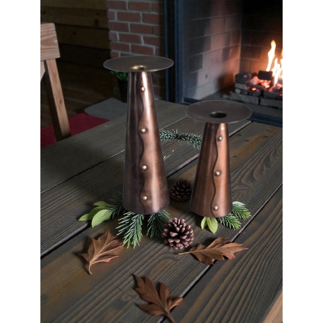 This product is a pair of copper finish metal candle holders in an Arts & Crafts style. The candle holders are designed in...