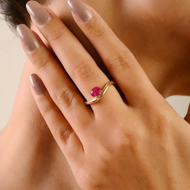 This elegant solitaire wave ring showcases a stunning 0.71-carat oval cut ruby, measuring approximately 5.8 x 4.6 mm,...