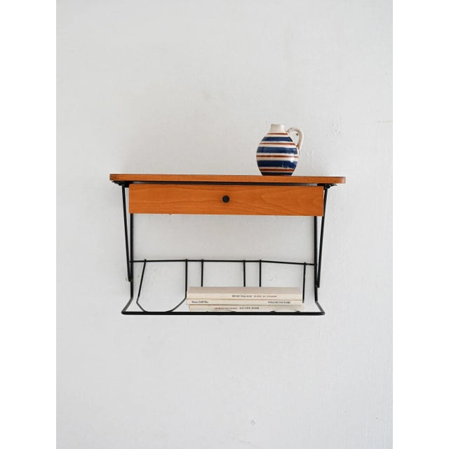 Elegant Scandinavian wall-mounted nightstand dating back to the 1960s, with a black-painted metal frame and a warm,...