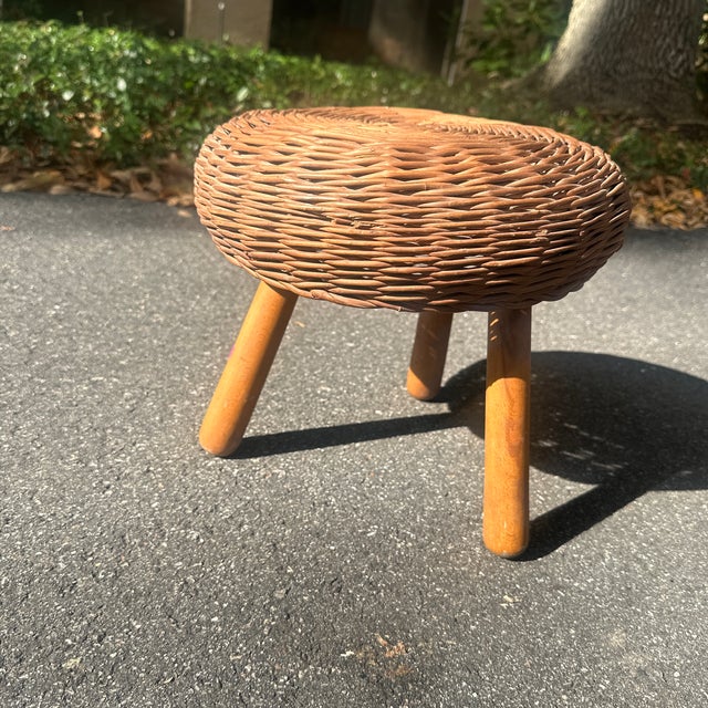 In the manner of Tony Paul, a three legged wicker stool with a wood base. Base is detached from top (that is how the piece...