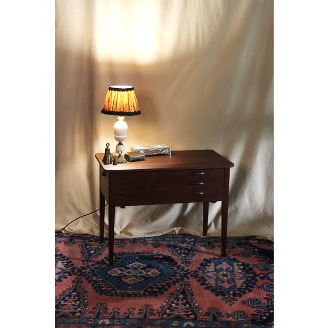 A wonderful Danish sewing table with very MCM style in teak or rosewood. Wood burn stamped with the Furniture Makers...