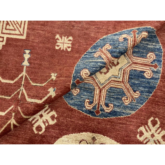 This stunning contemporary Khotan-designed hand-knotted wool rug features a vibrant rust field, beautifully complemented...