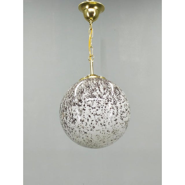 Vintage pendant light produced in czechoslovakia during the 1970s. The lamp features a spherical glass shade decorated...