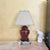 This vintage ginger jar table lamp features a richly glazed oxblood red ceramic body set on a dark wood or composite base,...