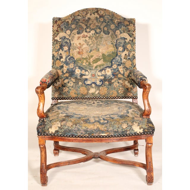 French Regence walnut armchair with tapestry upholstery, 18th century. With a tapestry upholstered back with brass nail...