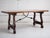 Spanish wooden dining table with rectangular top and scrolled trestle base. Features carved legs joined by wrought iron...