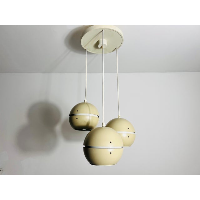 This cascading pendant lamp from the 1970s, crafted in the former GDR, embodies a striking mid-century modern aesthetic....