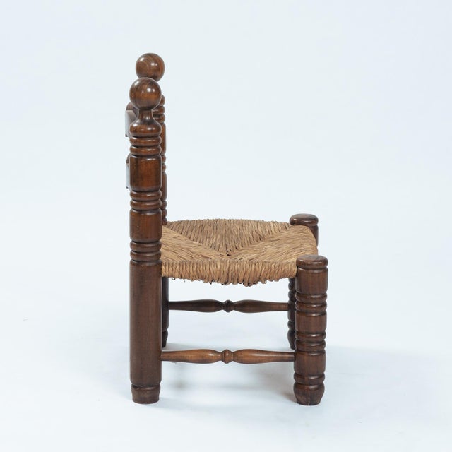 Wooden low chair with rush seat. Design of 1950s, in the style of Charles Dudoyt Handcrafted. In good solid condition with...