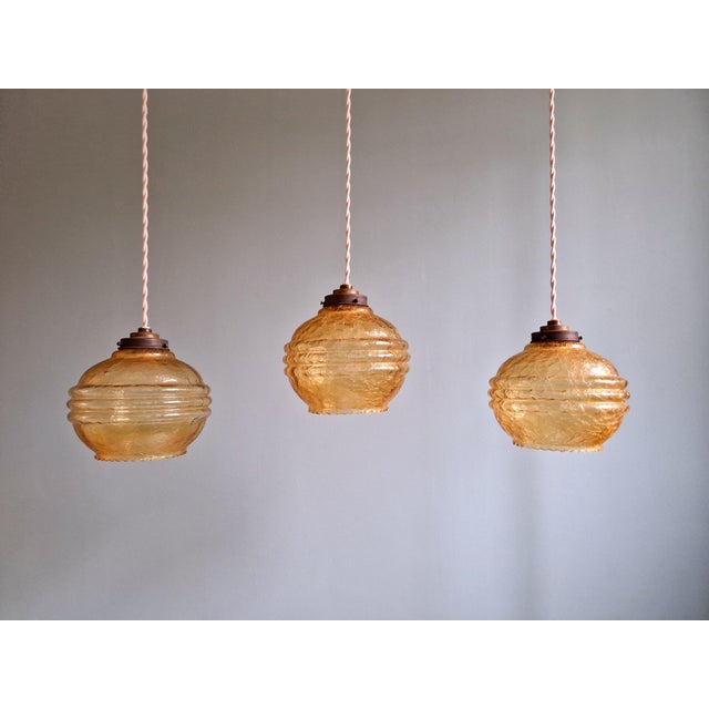 Trio of Art Deco pendant lights/portal lamps in amber cracked glass, 1920s-30s. Each of the pendant lights has been re-...