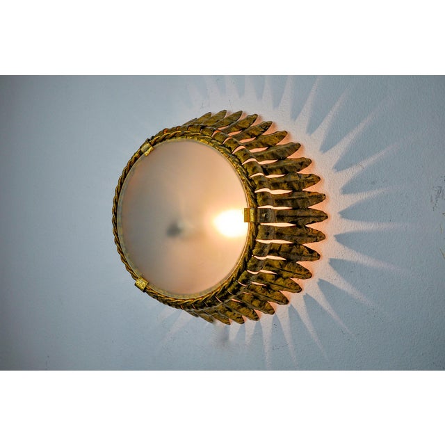 Large and rare sun wall light, designed and produced by Ferro Arte in Spain in the 1960s. Metal structure gilded with gold...