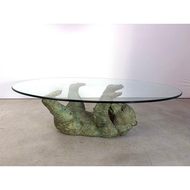 Eye-catching bronzed brass bear coffee table. Beautiful patinated look, nicely detailed sculpture with an oval clear glass...