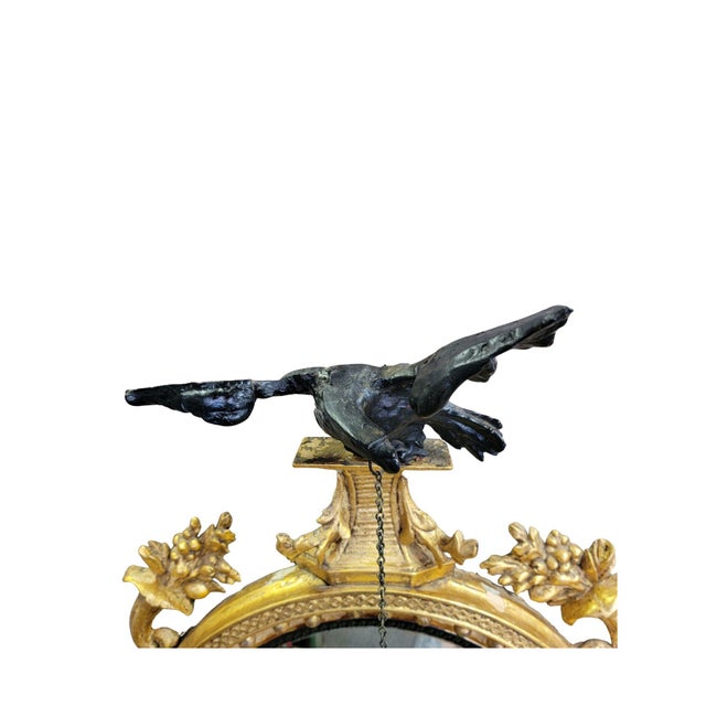 A Carved and Gilded English Regency Convex Mirror Surmounted by an Ebonized Eagle and Flanked by Cornucopia