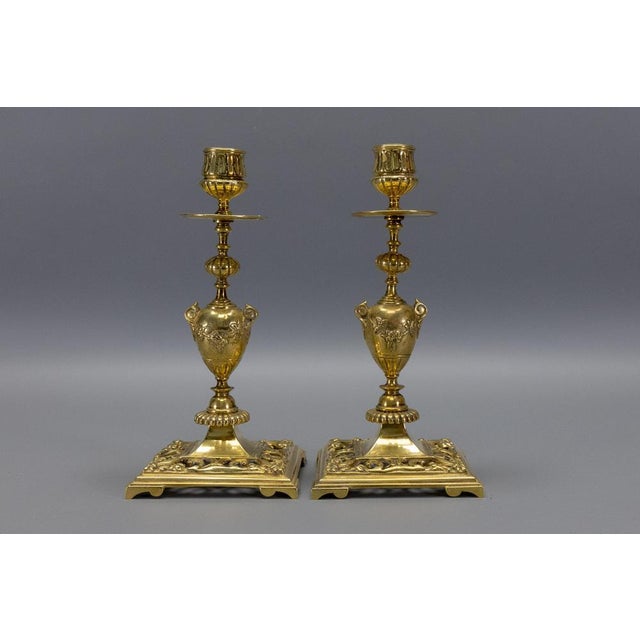 Elegant pair of French Neoclassical Revival bronze candlesticks from the 1930s, featuring urn-shaped stems and finely...