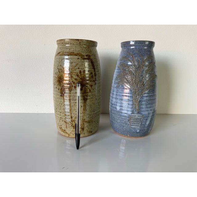 This charming pair of vintage studio art pottery vases by the artist Buk showcases a warm blend of rustic craftsmanship...